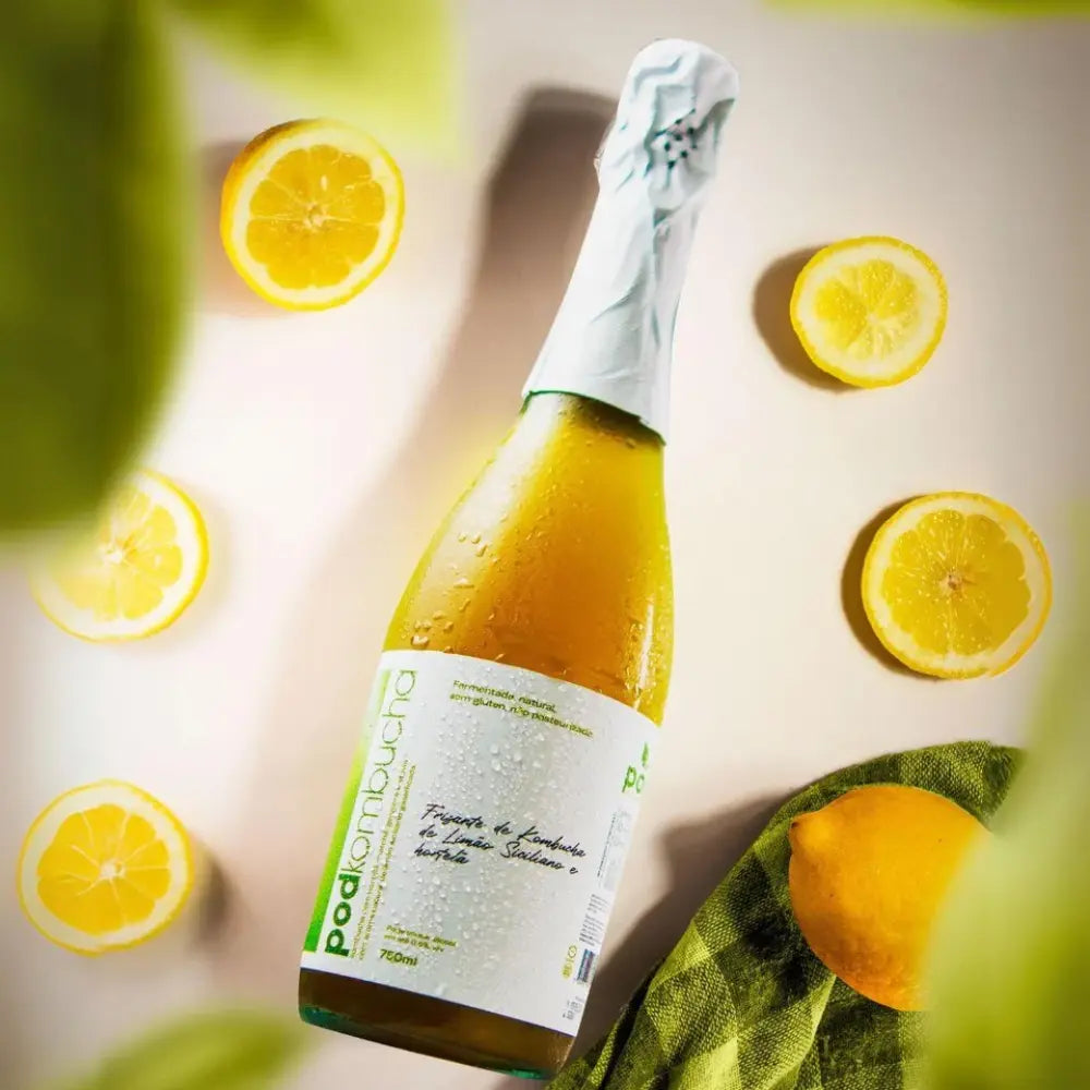 garrafa deitrada de espumante kombucha sem alcool de limao siciliano pod, com limões ao fundo