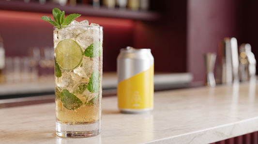 Drink sem álcool estilo mojito com hortelã, limão e gelo ao lado de uma lata de água tônica, alternativa ao rum sem álcool, em bar premium