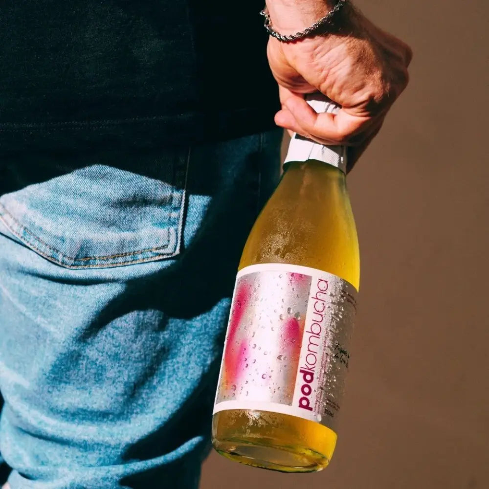 homem segurando garrafa de espumante kombucha sem alcool de uva pod